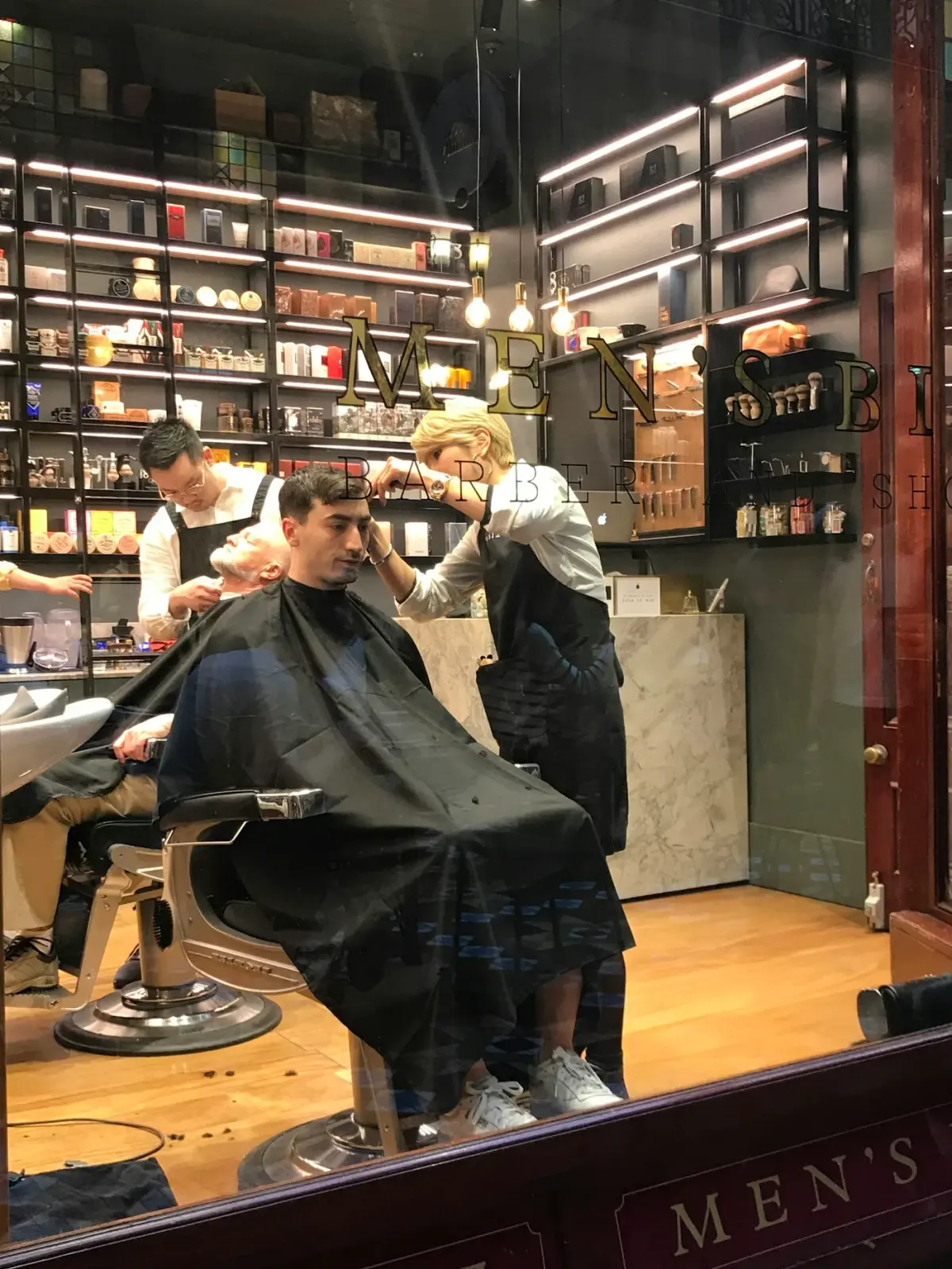 Profissionais trabalhando em uma barbearia, em fotografia de banco.